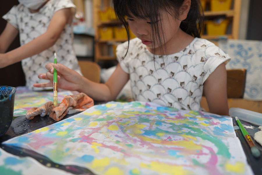 集中していろんな色で絵を描く子供