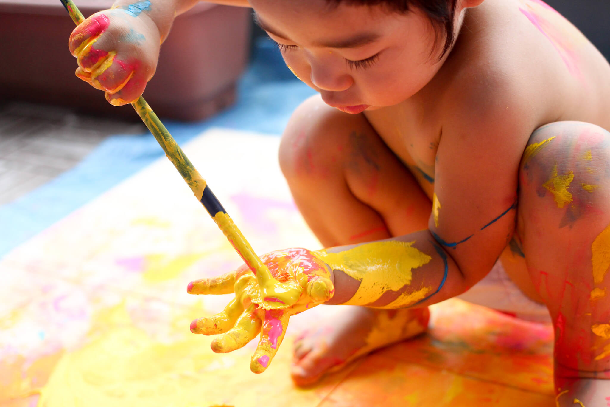 掌に鮮やかな黄色の絵の具を付けている子供の写真