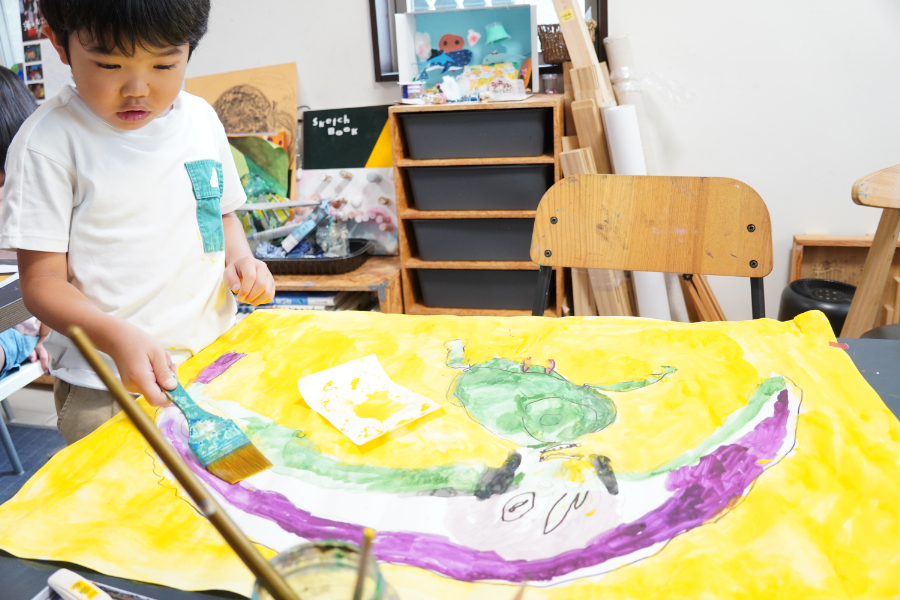 鮮やかな黄色と紫の絵を書いている子供